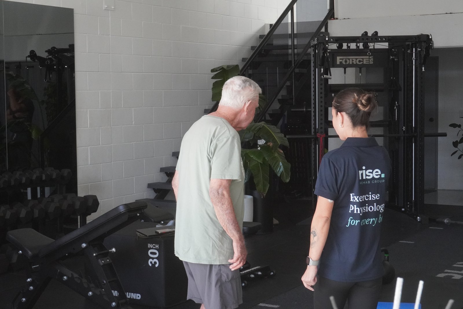 Isabelle McMullen walking alongside a client during a session at Rise Rehab Group's Burleigh Heads location
